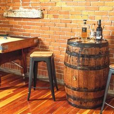 two stools next to a wooden barrel with bottles on it