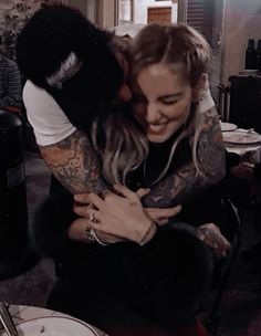 a woman hugging a man with tattoos on his arms