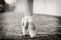 a black and white photo of a woman's legs wearing ballet shoes