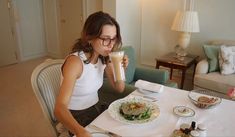 a woman sitting at a table in front of a plate with food on it and a drink