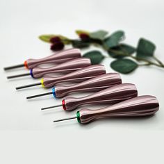 six toothbrushes lined up in a row with colored tips and flowers behind them