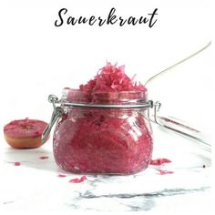 red cabbage in a glass jar with spoons next to it and text overlay reading red cabbage apple, chili & ginger sauerrkraut