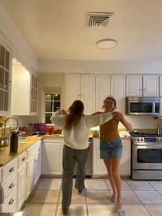 two people are dancing in the kitchen together