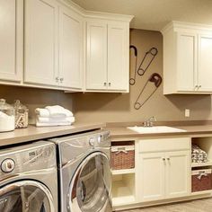 a washer and dryer in a room with white cupboards, cabinets and drawers