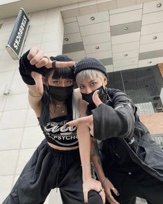 two people wearing black clothing and one is holding up a can with the word destroy written on it