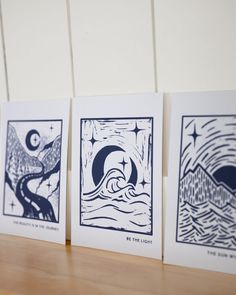 three cards with designs on them sitting on a table