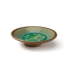 a green and brown bowl sitting on top of a white table