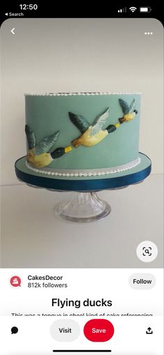 a cake decorated with birds on top of a blue plate and the words flying ducks above it