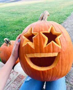 a person holding up a carved pumpkin in front of their face