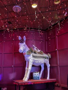 a large white horse statue sitting on top of a wooden table in front of a red wall