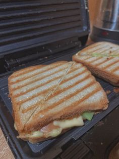 two grilled sandwiches sitting on top of an electric grill