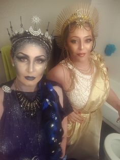 two women dressed in costumes posing for a photo next to a toilet with their faces painted gold and silver