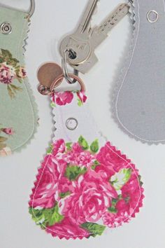 two keychains with pink flowers on them and one has a flowered tag attached to it