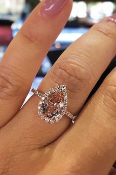 a woman's hand with a pink diamond ring on top of her left finger