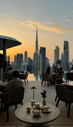 people are sitting at tables in front of the city skyline