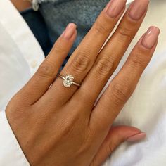 a woman's hand with a diamond ring on her left hand and pink manicured nails