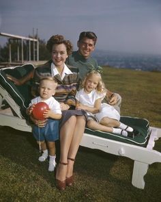 a man, woman and two children are sitting on a bench with a ball in their hands