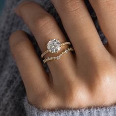 a woman's hand with a diamond ring on top of her finger and an engagement band