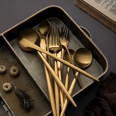 there are many spoons and forks in the box with doughnuts on the table