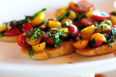 small pieces of bread topped with vegetables on top of a white plate