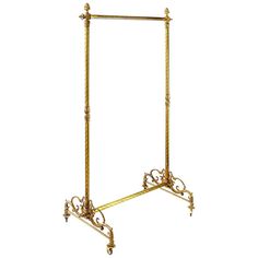 an ornate gold metal garment rack with wheels and bars on one end, the other side is