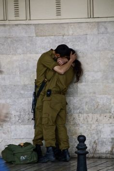 two people hugging each other in front of a wall