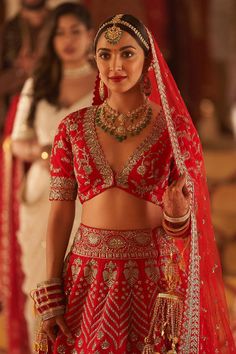 a woman in a red and gold bridal outfit standing next to two other women