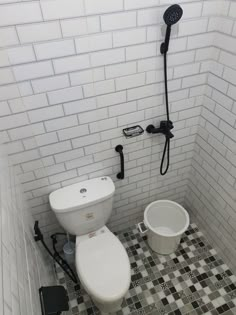 a white toilet sitting next to a black and white bucket on top of a tiled floor