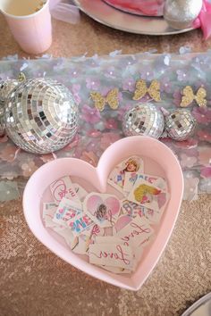 a pink heart shaped box sitting on top of a table filled with confetti