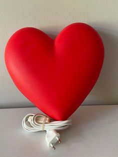 a red heart shaped pillow sitting on top of a table next to a charger