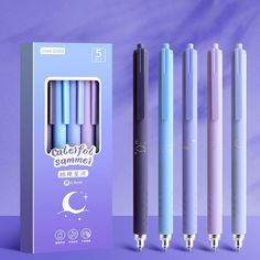 three different colored pens are next to each other in front of a purple box with the same design on it