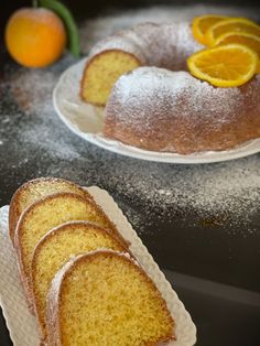 slices of orange pound cake on plates with powdered sugar and fresh fruit in the background