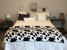 a bed with black and white cow print comforter on top of it's headboard