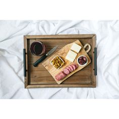 a wooden tray topped with meat and cheese next to a cup of coffee on top of a bed