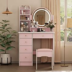 a pink vanity with a mirror and stool in a room next to a potted plant