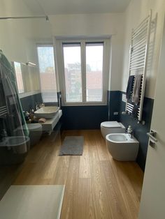 a bathroom with two sinks, toilet and bathtub next to each other in front of large windows