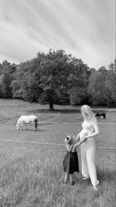 a woman and child are standing in the grass