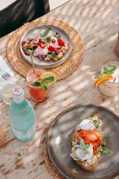 a table topped with plates and drinks on top of a wooden table covered in food