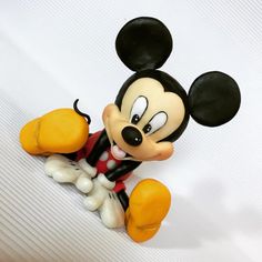 a mickey mouse figurine sitting on top of a white sheet with black and yellow ears