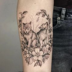 a couple of foxes sitting on top of a flower filled arm tattoo design with flowers and leaves