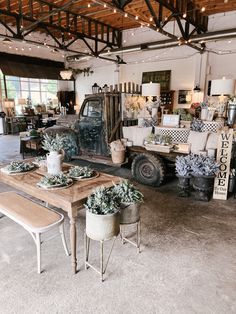 a room filled with lots of furniture and plants on top of wooden tables in front of a truck