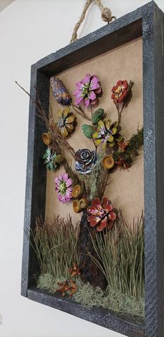 a wooden frame with flowers and plants in it hanging from the side of a wall