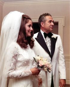 a man and woman in wedding attire standing next to each other at the altar together