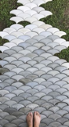 a person standing on top of a stone floor next to an umbrella shaped area with grass in the background