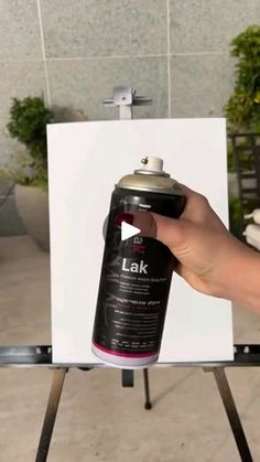 a person holding a spray paint can in front of an easel