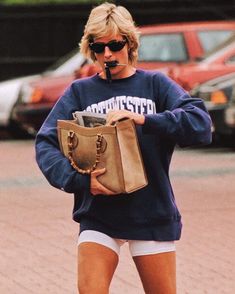 a woman walking down the street with a purse in her hand and sunglasses on her face