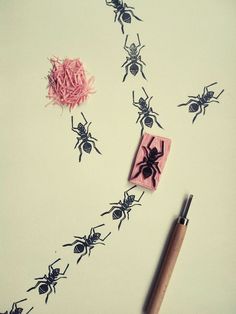 some black and pink bugs on a white surface with a pen next to it,