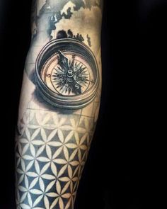 a man's arm with a compass tattoo on it