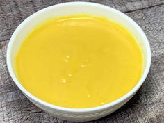 a white bowl filled with yellow liquid on top of a wooden table