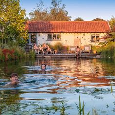 some people are swimming in the water near a house